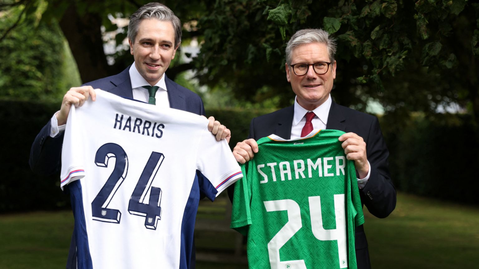 Taoiseach Simon Harris and Prime Minister Sir Keir Starmer holding up football jerseys with their surnames on the back of each shirt, along with the number 24. 