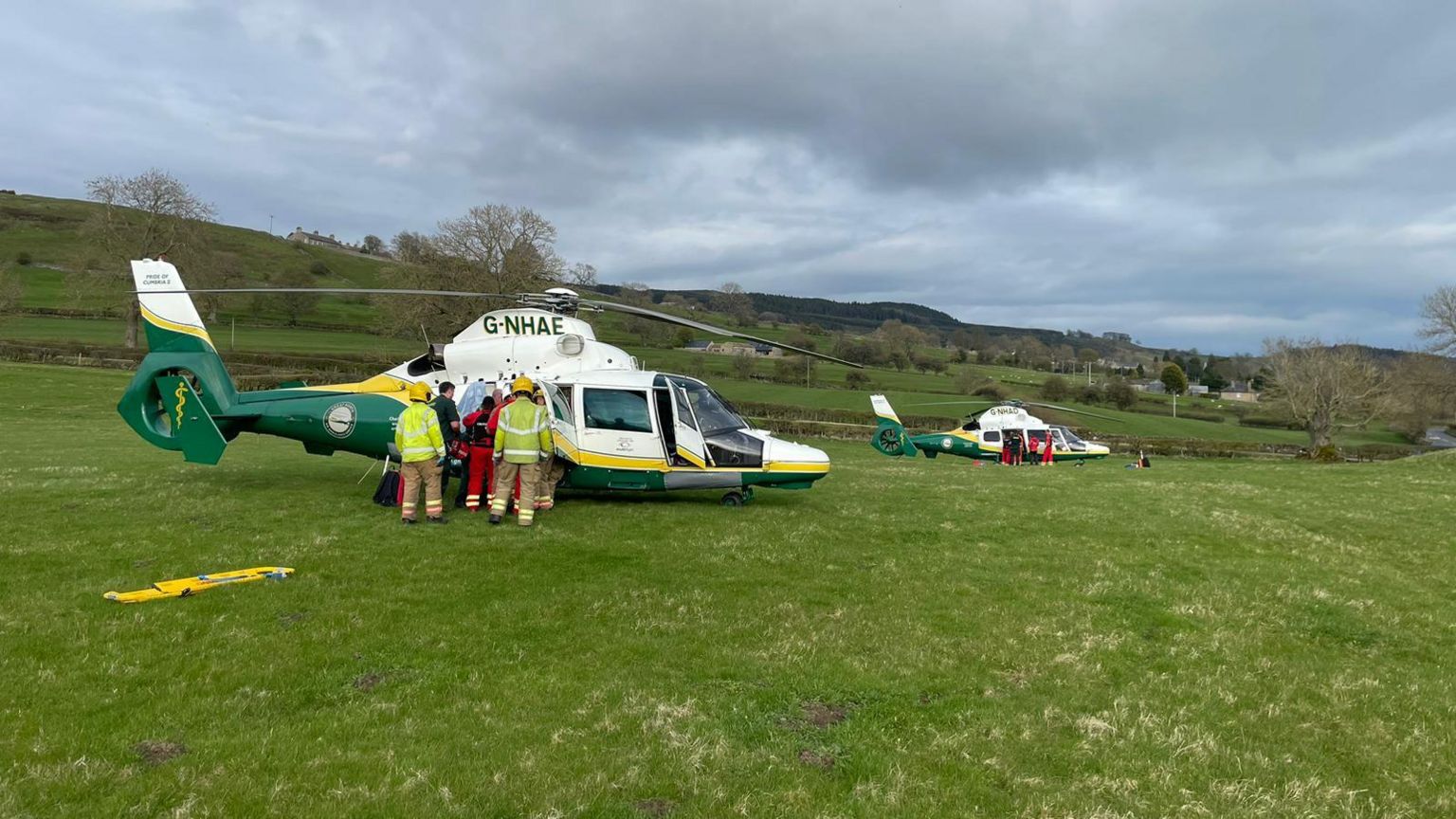 Two helicopters in a field with paramedics loading the teenagers on