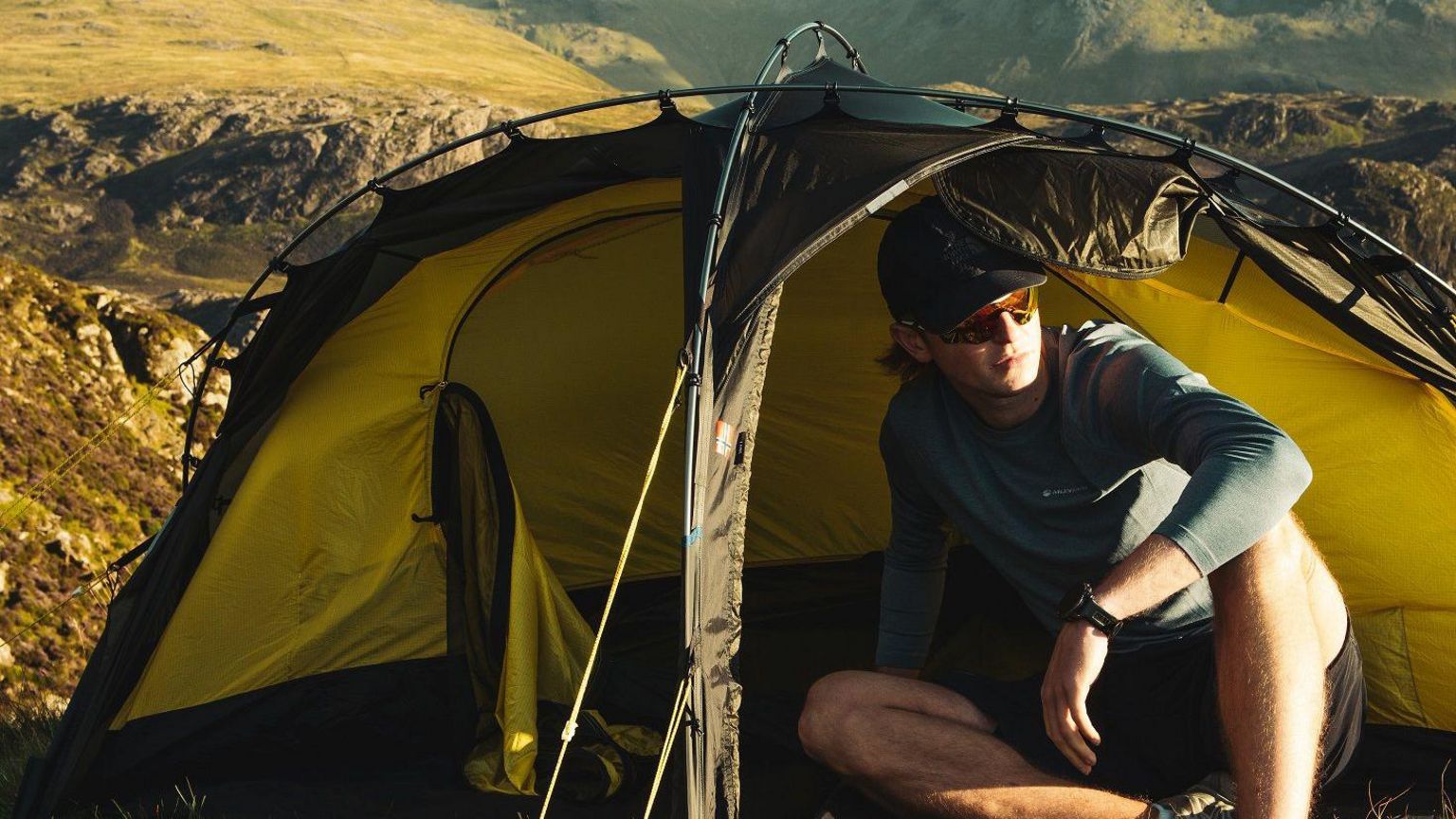 Outdoor influencer sitting in front of a tent on mountain in the Buttermere area