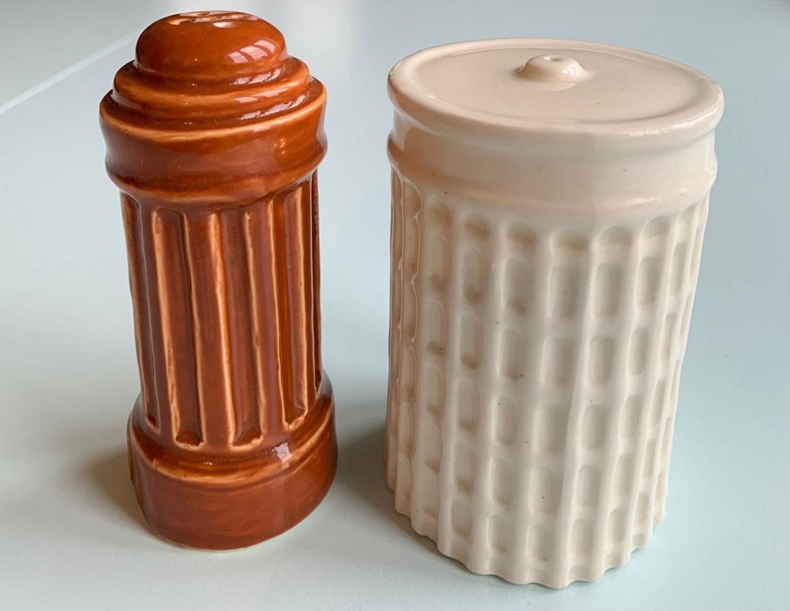 A close-up view of the ceramic salt and pepper pots. A white one, on the right, is for salt and a brown one is for pepper.