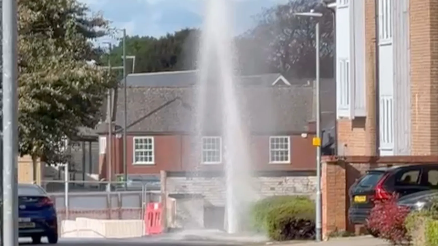 A jet of water is spaying into the air near some resedential houses