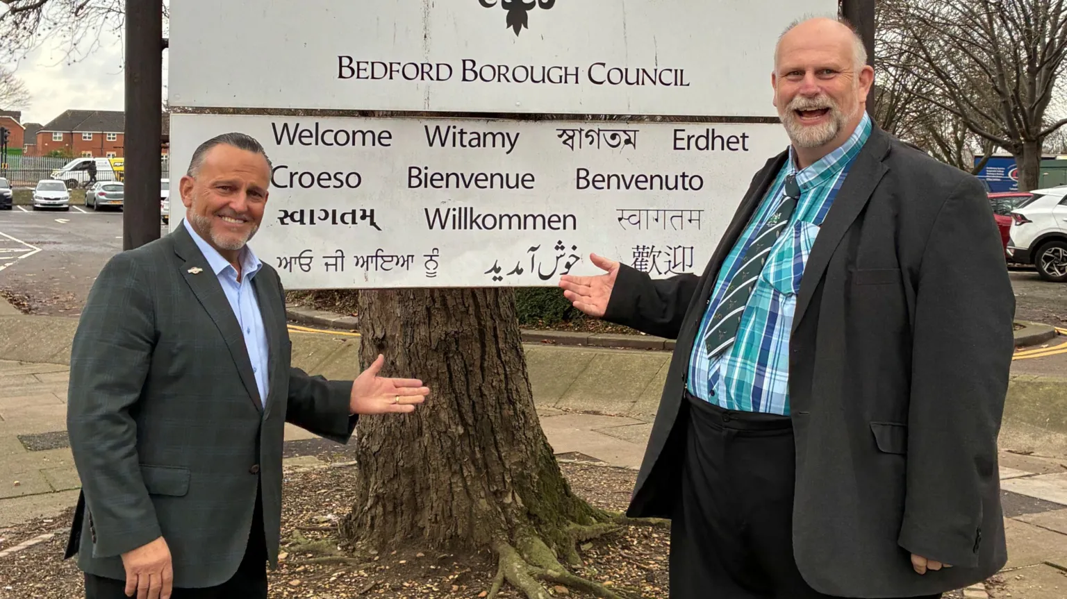 Bedford Borough Council Two men smiling in front of a sign that says "Bedford Borough Council".