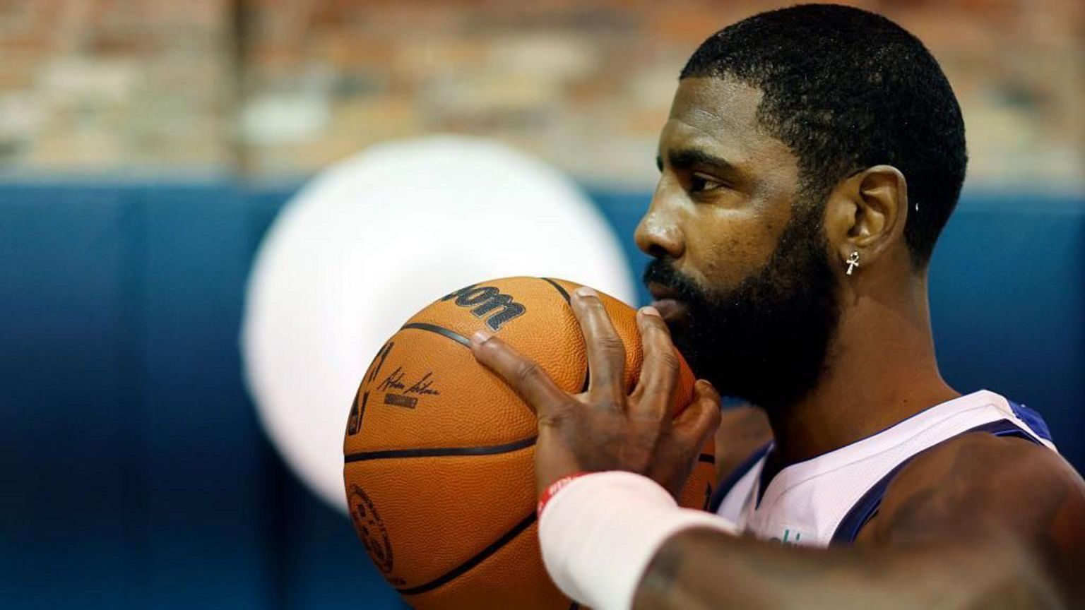NBA球星凯里·厄文（Kyrie Irving）将一颗印有Wilson品牌的篮球托在下巴前