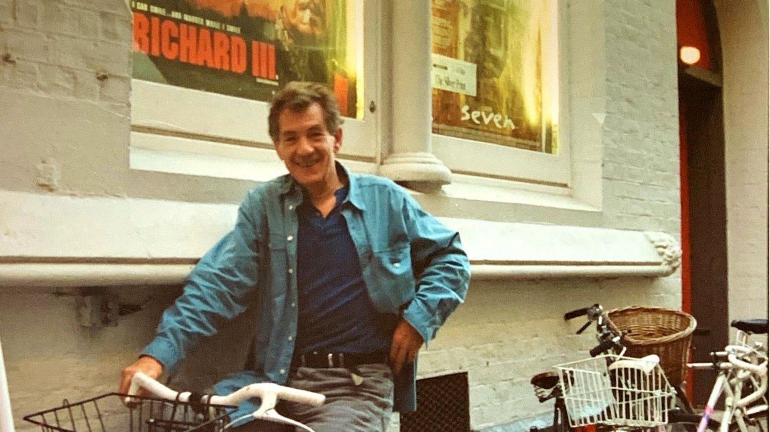 Sir Ian McKellen outside the Cambridge Arts Theatre on a bike 