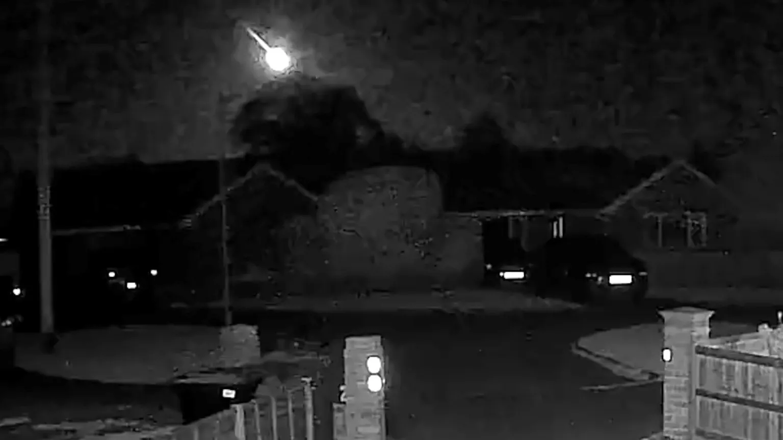 A doorbell camera image at night with a bright meteor flying across the sky.