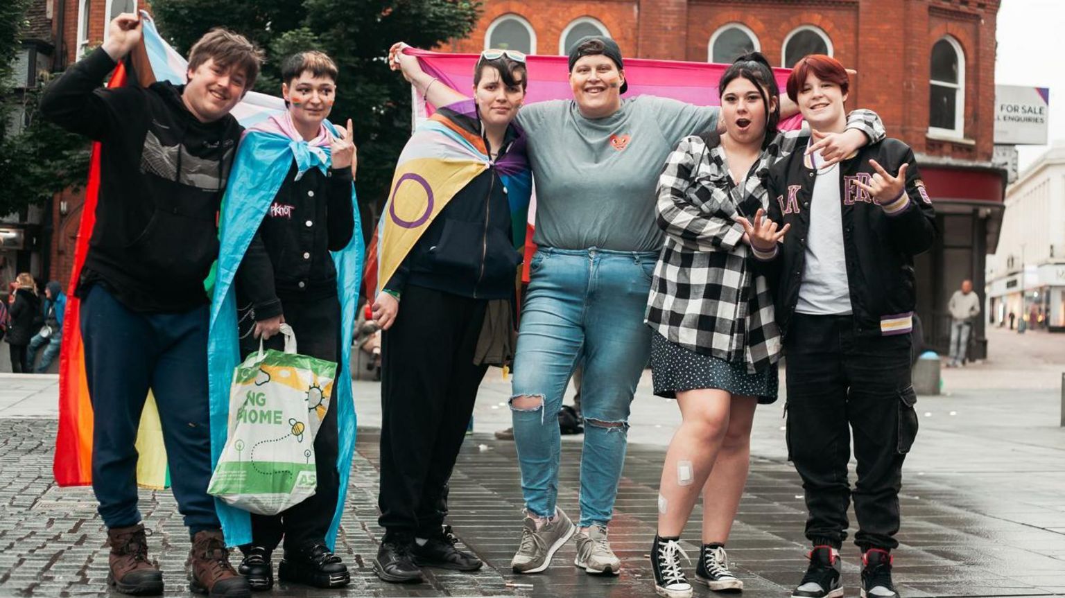 A group of six people holding Pride flags