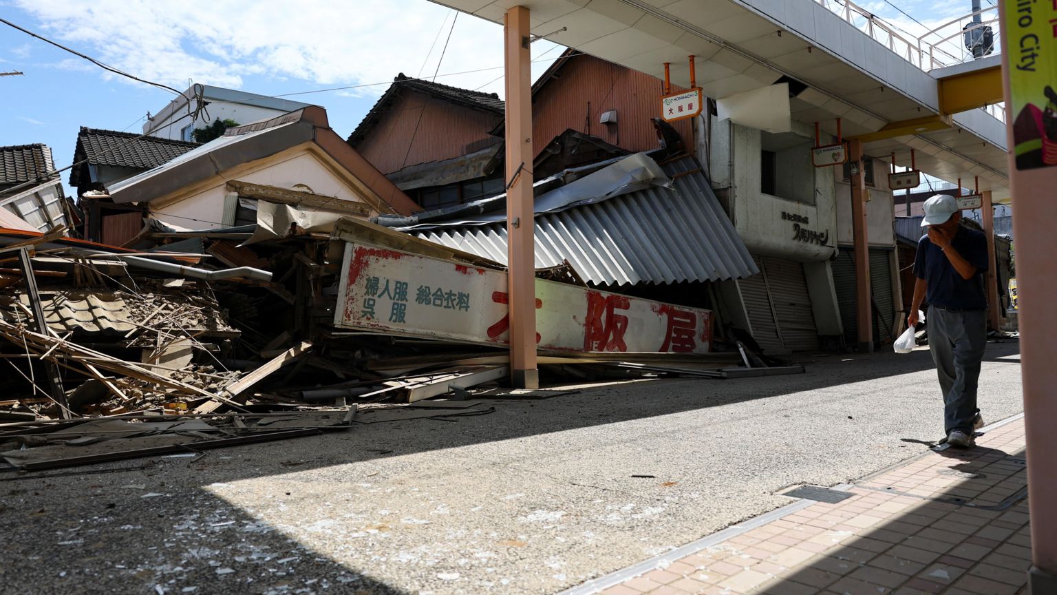2026年7月29日，日本熊本县八代市，一名行人走过因熊本县6.8级地震而倒塌的商店