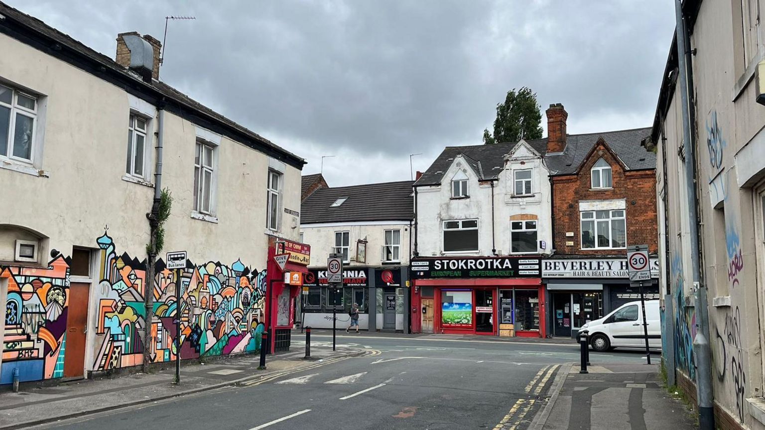 View of graffitied cream-coloured buildings on Cave Street