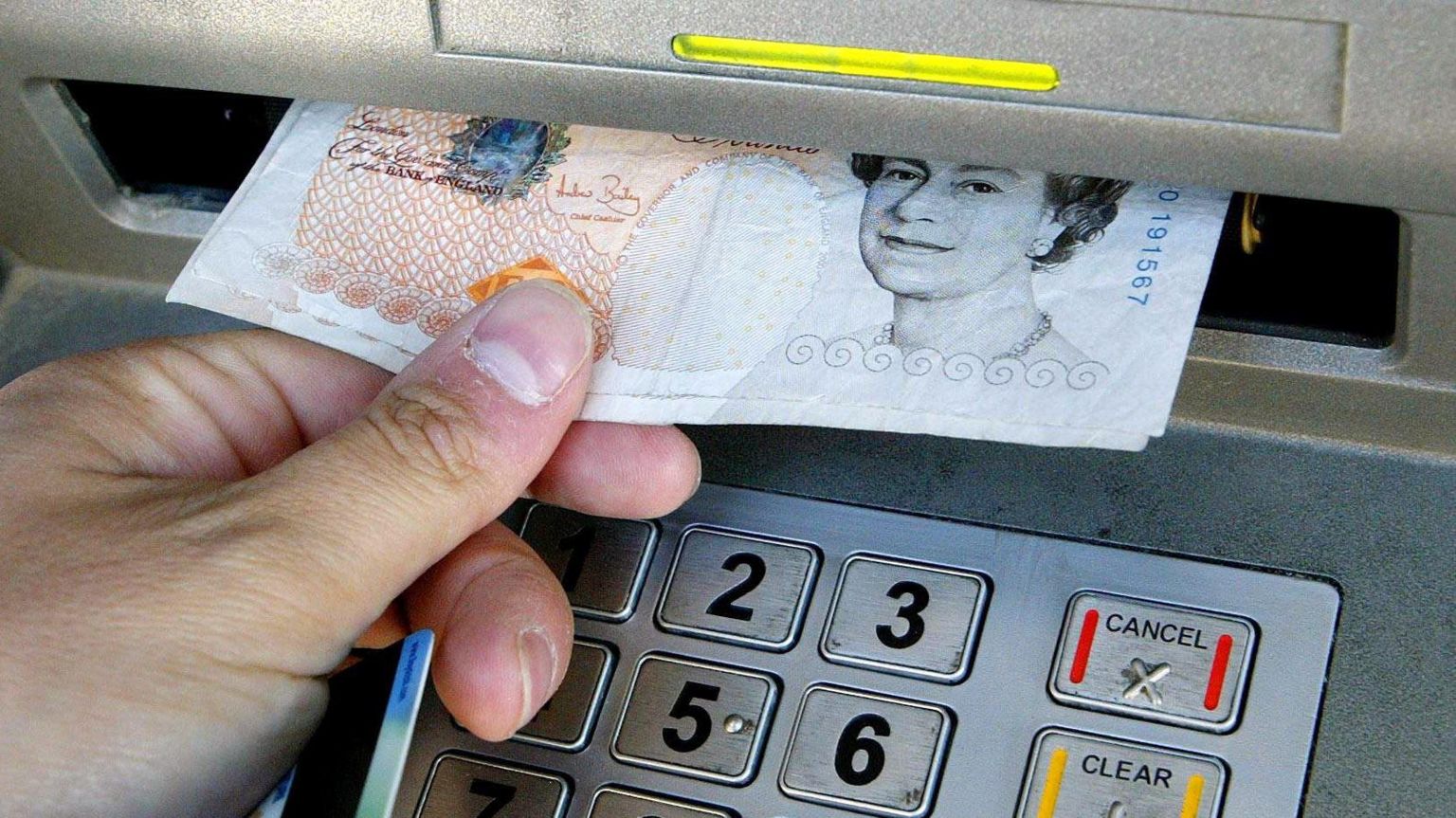 A hand taking cash out of an ATM