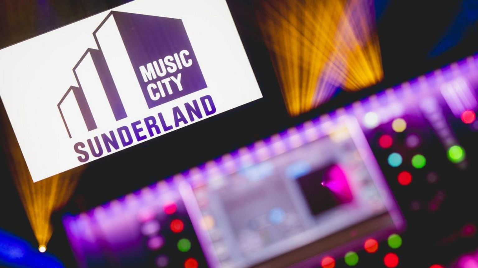 Music City Sunderland logo with a blurred DJ laptop screen in the foreground