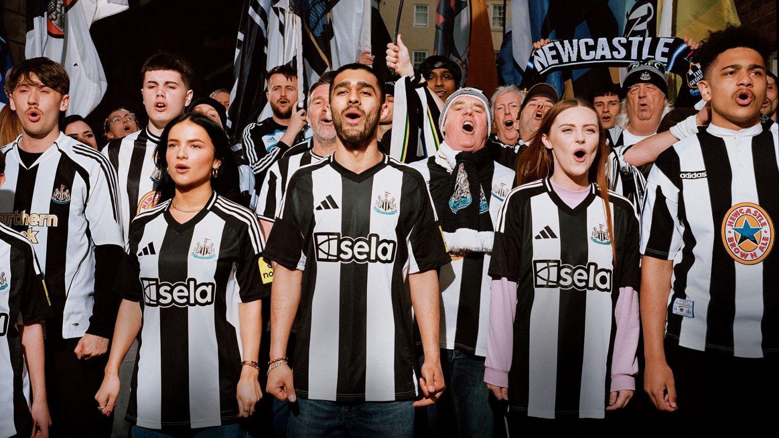 Fans wear Newcastle United's new home shirt alongside supporters decked out in previous Adidas jerseys