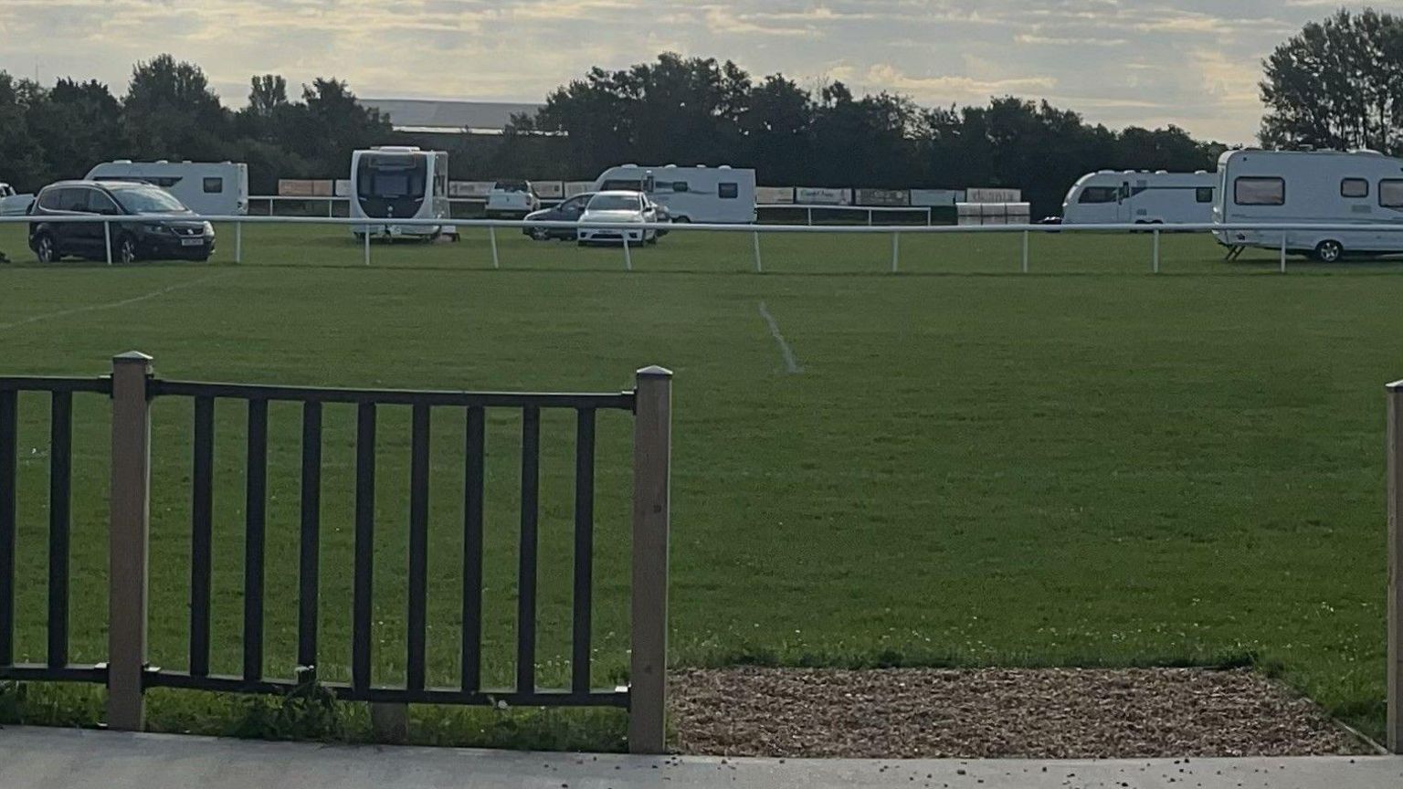 A number of caravans and cars parked close together on a green field.