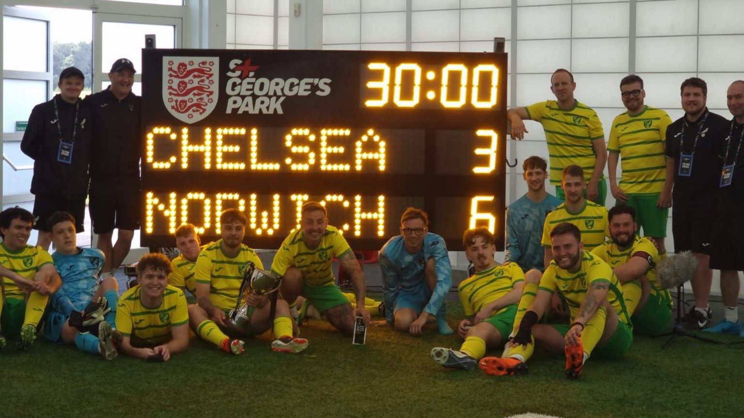 Norwich City CP team in front of the scoreboard that reads 6-3