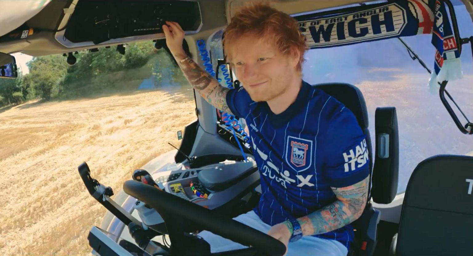 Singer Ed Sheeran pictured driving the Ipswich Town tractor through a field