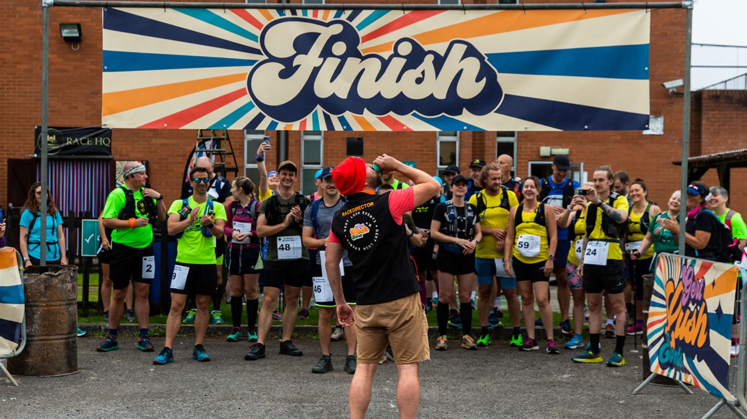 Paul Breen downing a drink in front of participants of another event at the finish line