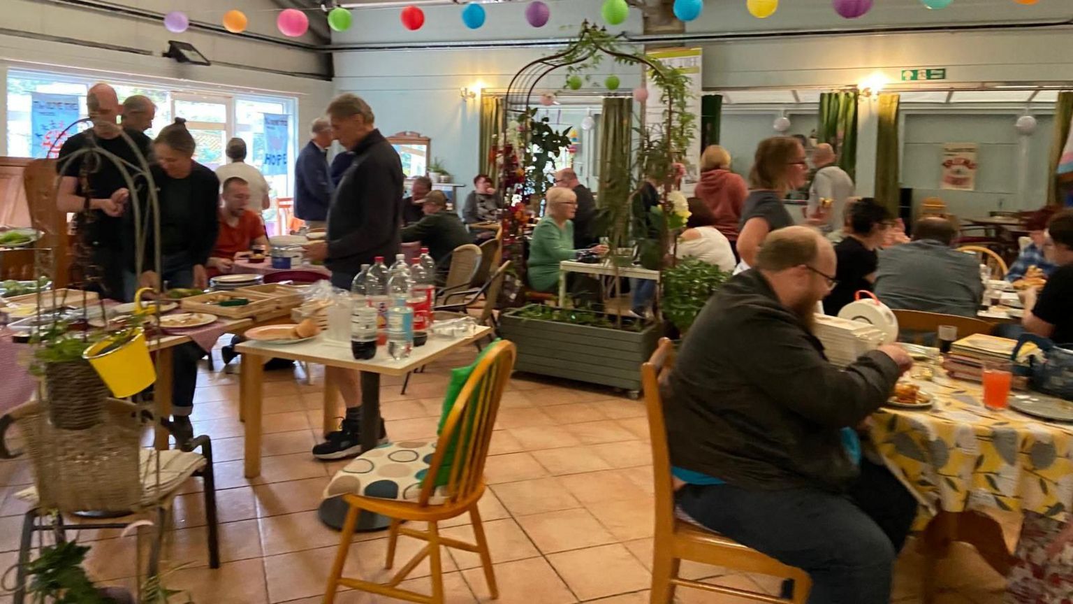 A busy cafe with customers sat at tables around the room being served