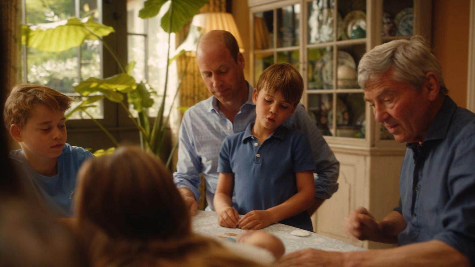 William, Prince Louis, Prince George, their maternal grandfather Michael Middleton are seen playing a card game at a table 