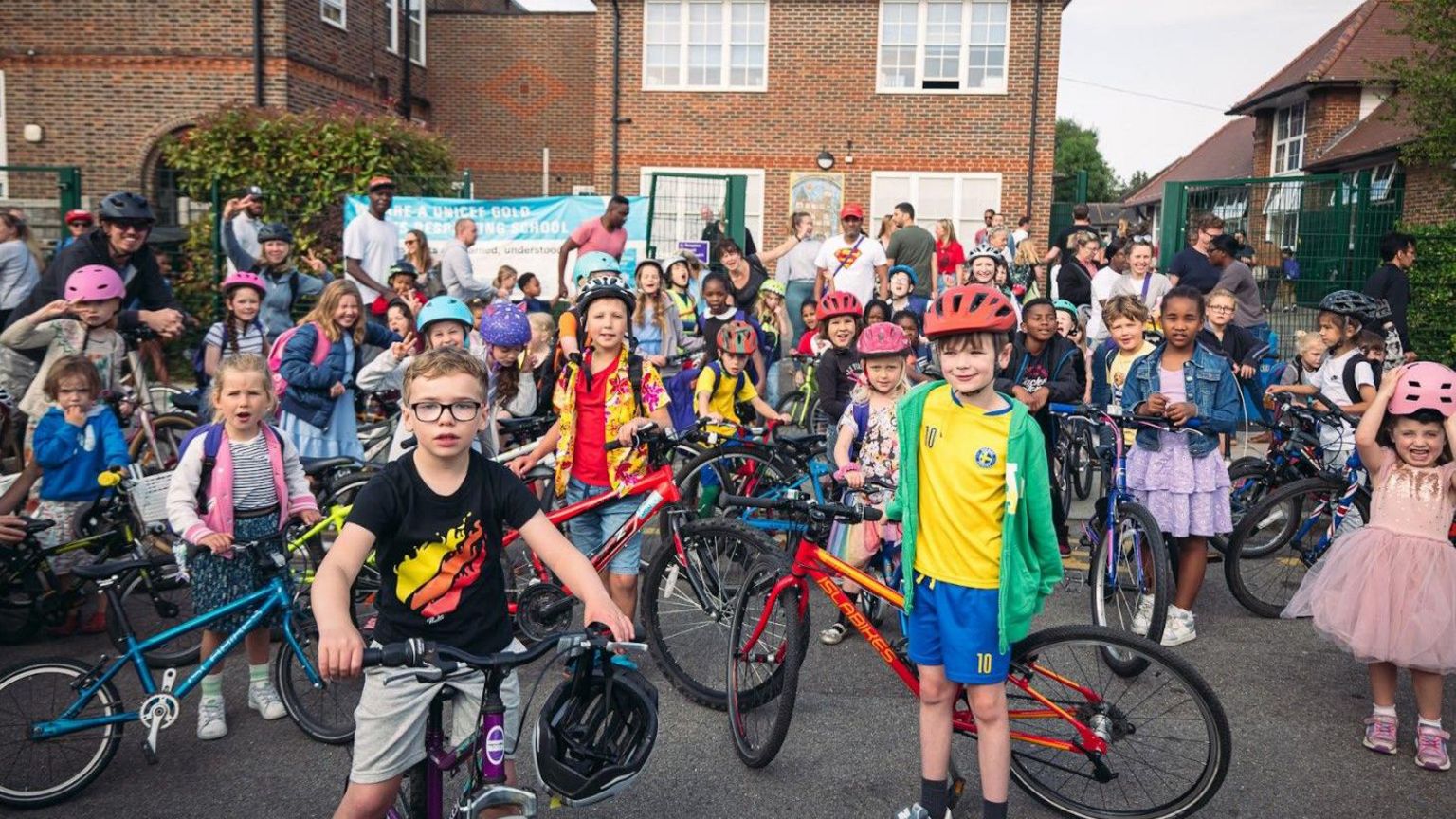 Children wearing cycling helmets stand in front of their bikes