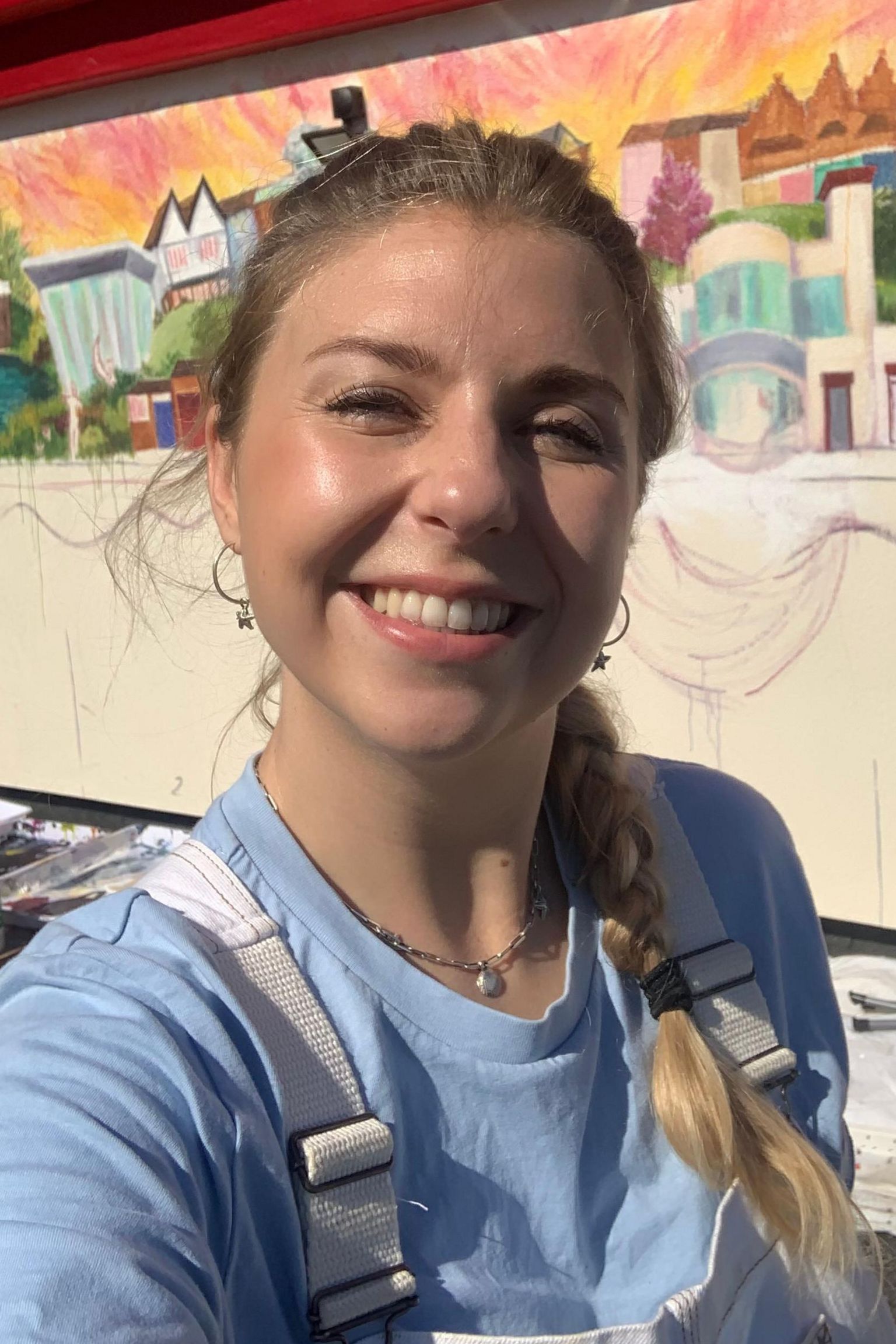 Francesca Young, artist of a mural in Cleethorpes, she has blonde hair and is smiling in a selfie in front of her artwork