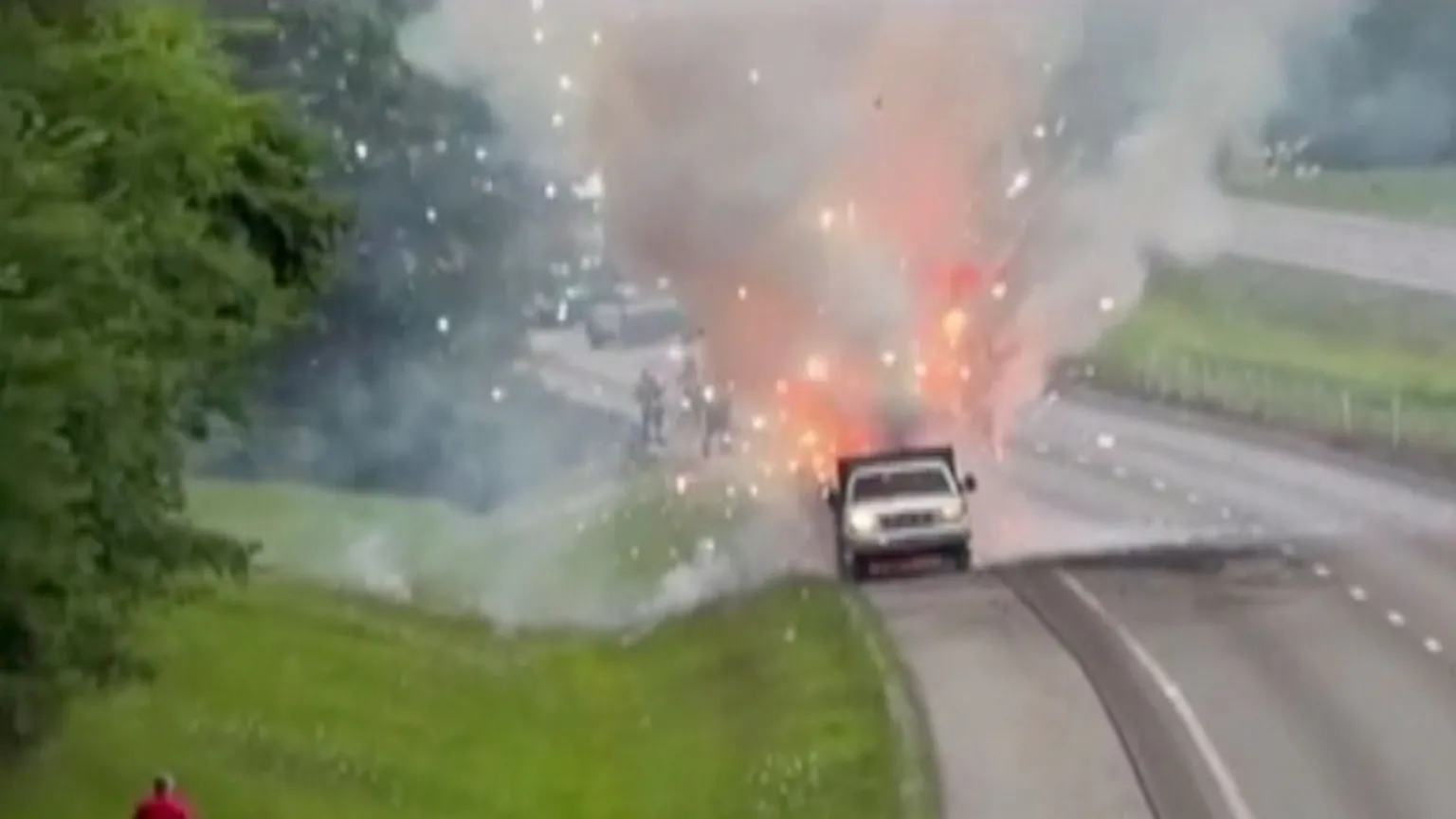 Fireworks shoot out of a pick up truck on the side of a highway.