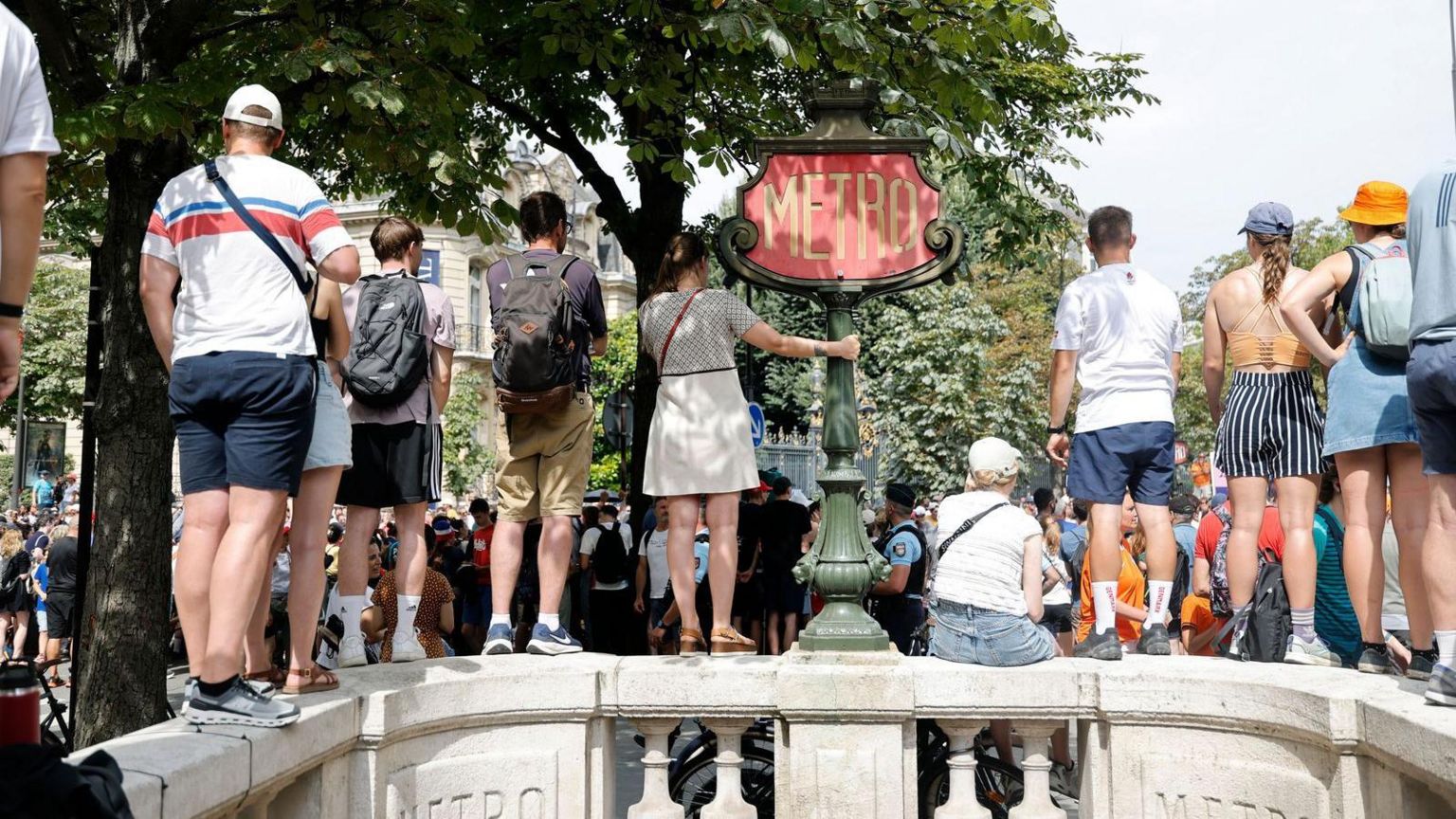 People climb on a wall to watch sport during the Paris Olympics