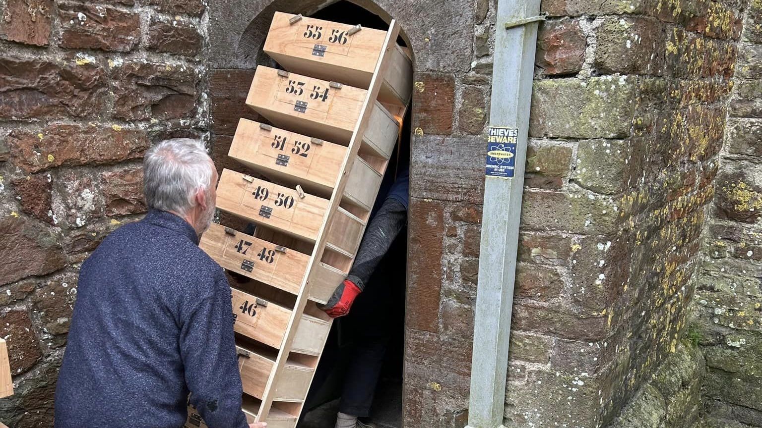 Two men trying to get the nesting box cabinets through a very narrow doorway.