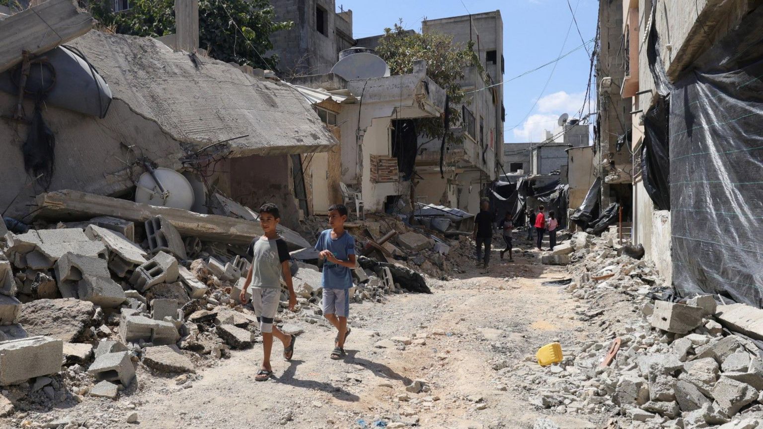 Palestinians walks on top of rubble from buildings and a road damaged during a two-day Israeli army operation in Tulkarm, in the occupied West Bank (30 August 2024)