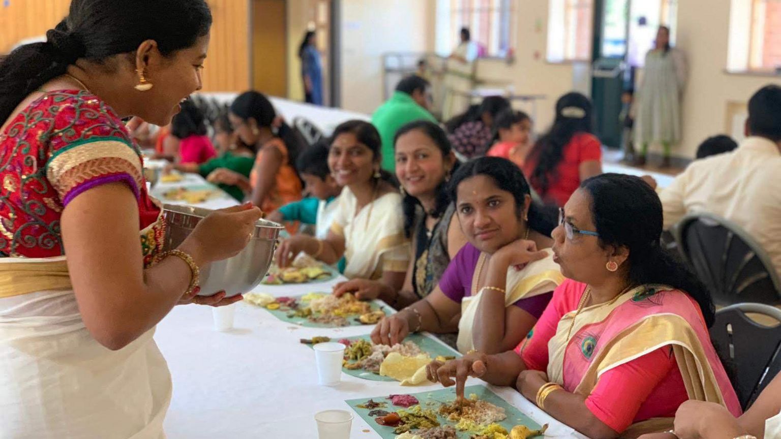 People eating food at an Onam harvest festival