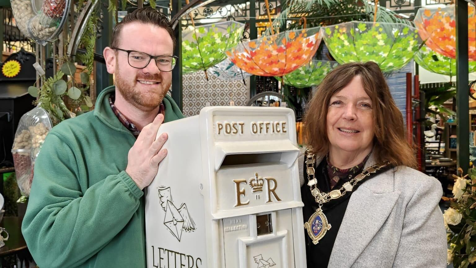 A man and woman holding a postbox