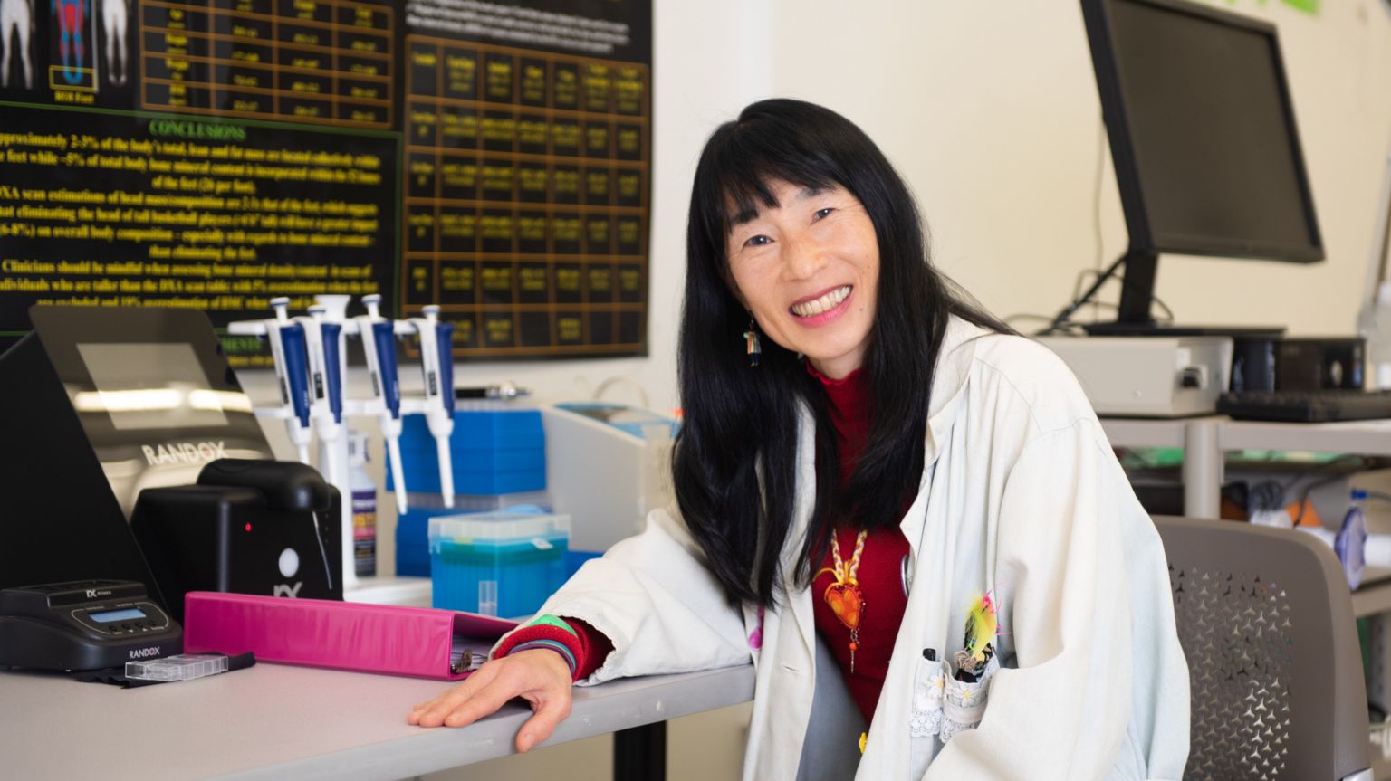 塔玛拉·休—巴特勒身穿实验服,坐在实验室的桌子旁。