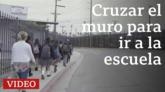 Estudiantes mexicanos caminando junto al muro fronterizo para ir al colegio en Estados Unidos.