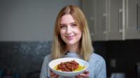 Young woman holding bowl of vegan food