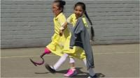 Anu, de 7 anos, aparece pela primeira vez na escola com sua 'nova perna cor-de-rosa' e é recebida por colegas.