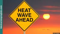 A yellow-diamond sign with 'Heatwave ahead' printed on it in front of a blazing hot yellow sun