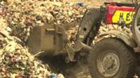 Digger shovelling waste plastic
