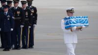 A solider carries a box believed to contain human remains