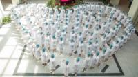 A crowd of nurses stand in the shape of a heart as they recite an oath