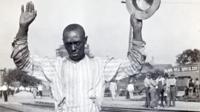 A black man holds his hands up