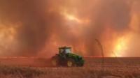 Un tractor delante de llamas y humo.