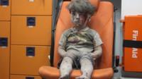A boy sits in shock after an explosion