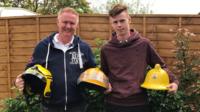 Andy and son John holding firefighter helmets