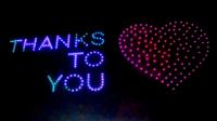 Lights in the sky spell out "thanks to you" with a heart symbol