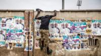 Man climbs up wall with election posters