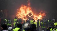 Demonstrators stand in front of a burning car during a protest of Yellow vests (Gilets jaunes)
