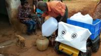 A water carrying robot stands next to a man pouring water