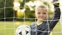 Boy with football in goal