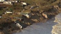 Homes slide into the sea after last year's tidal surge