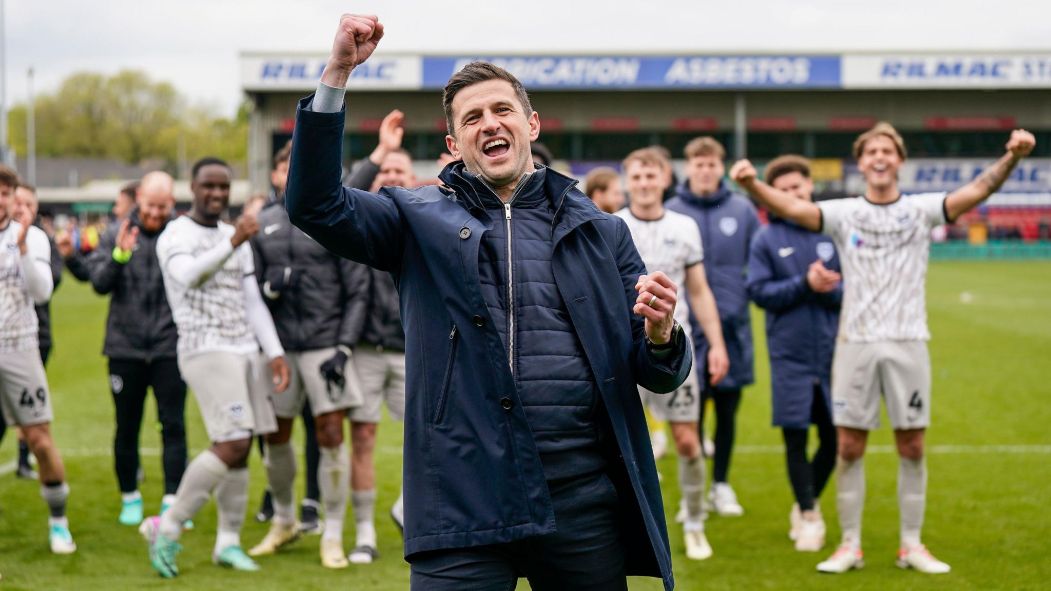 John Mousinho celebrating with his players after securing promotion from League One 
