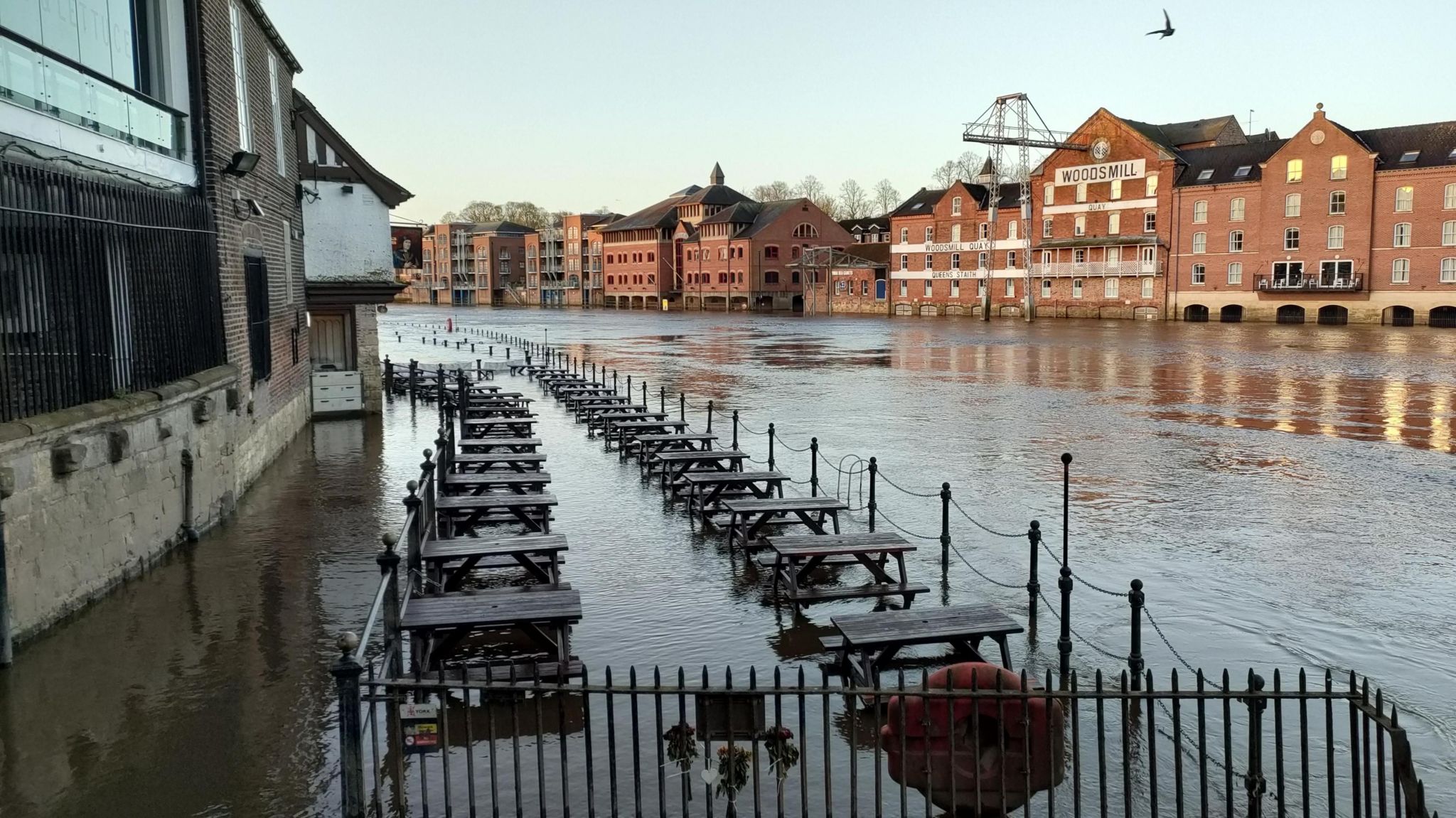 Flooded river extending onto an outdoor seating area along the riverbank. 