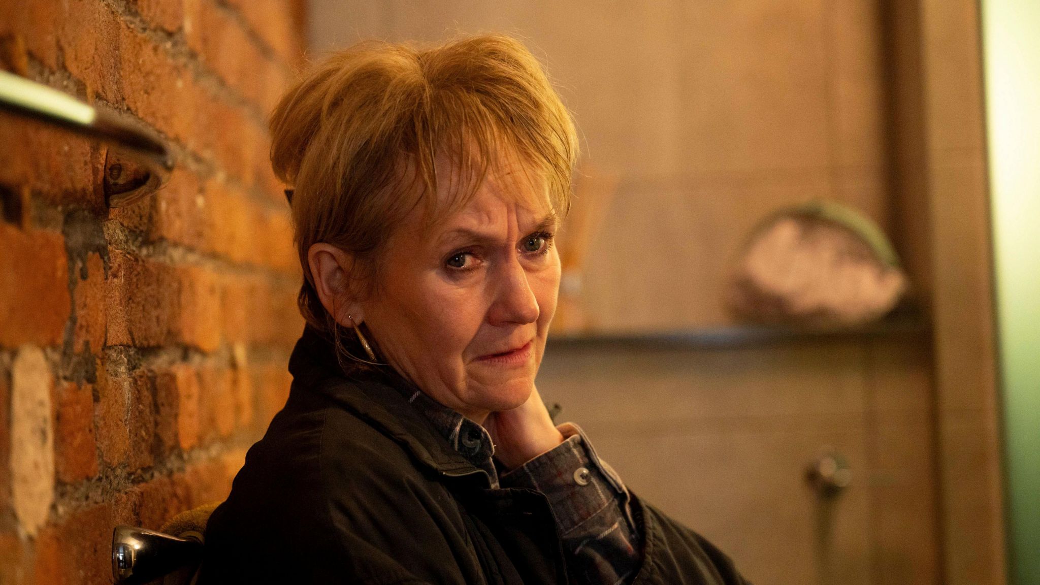 Daphne Sparrow, played by Lorraine Ashbourne, leaning against a wall looking pensive